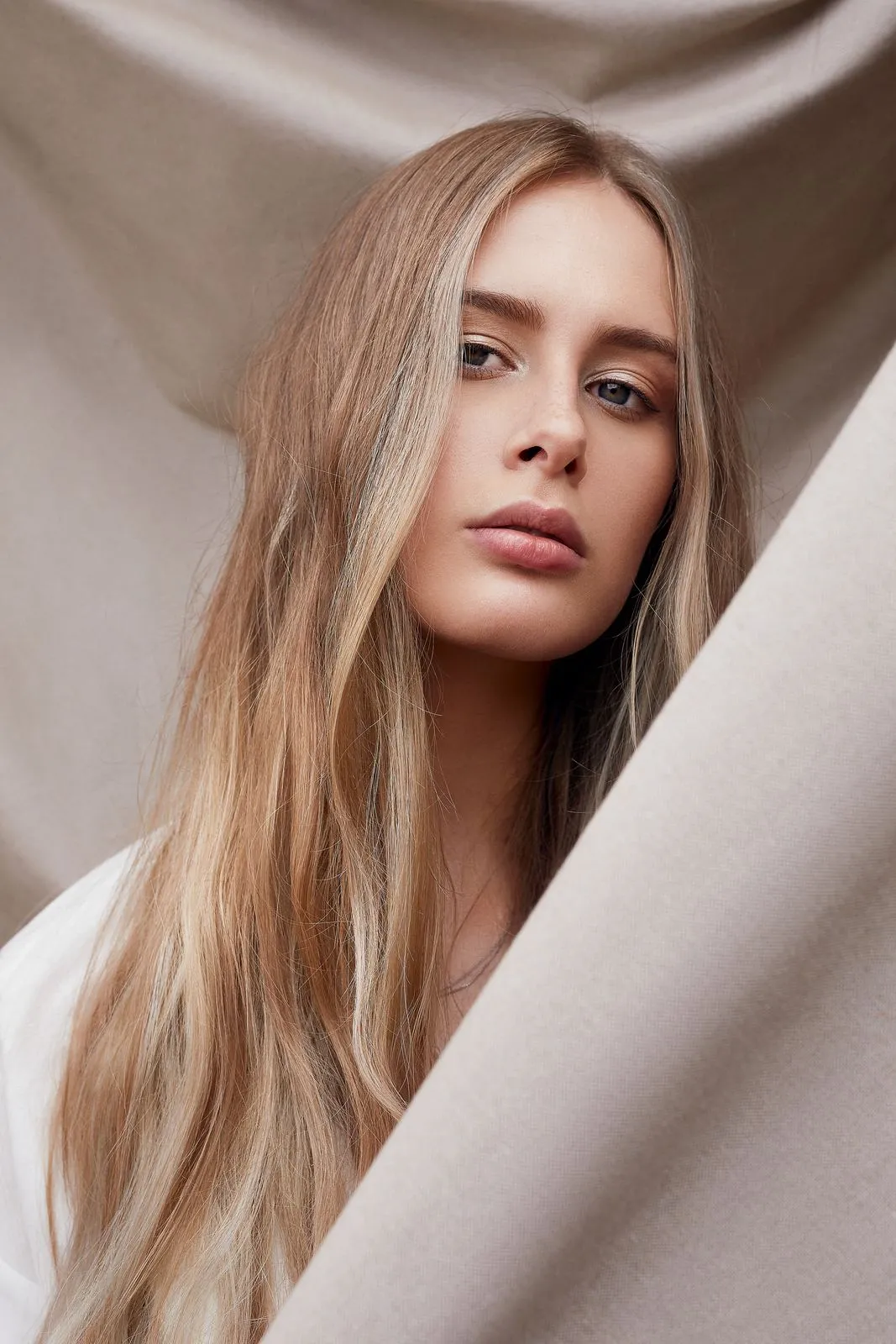 Model mit langem Blonde zwischen Stoffbahnen